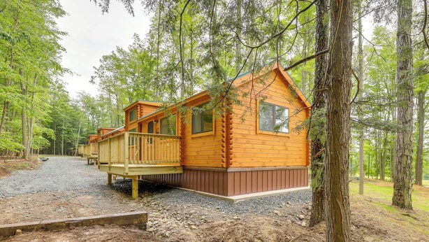 Eine Holzhütte mit einer Terrasse, umgeben von Bäumen.