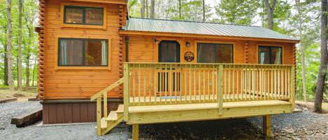 A wooden cabin with a deck and a staircase leading to the entrance.