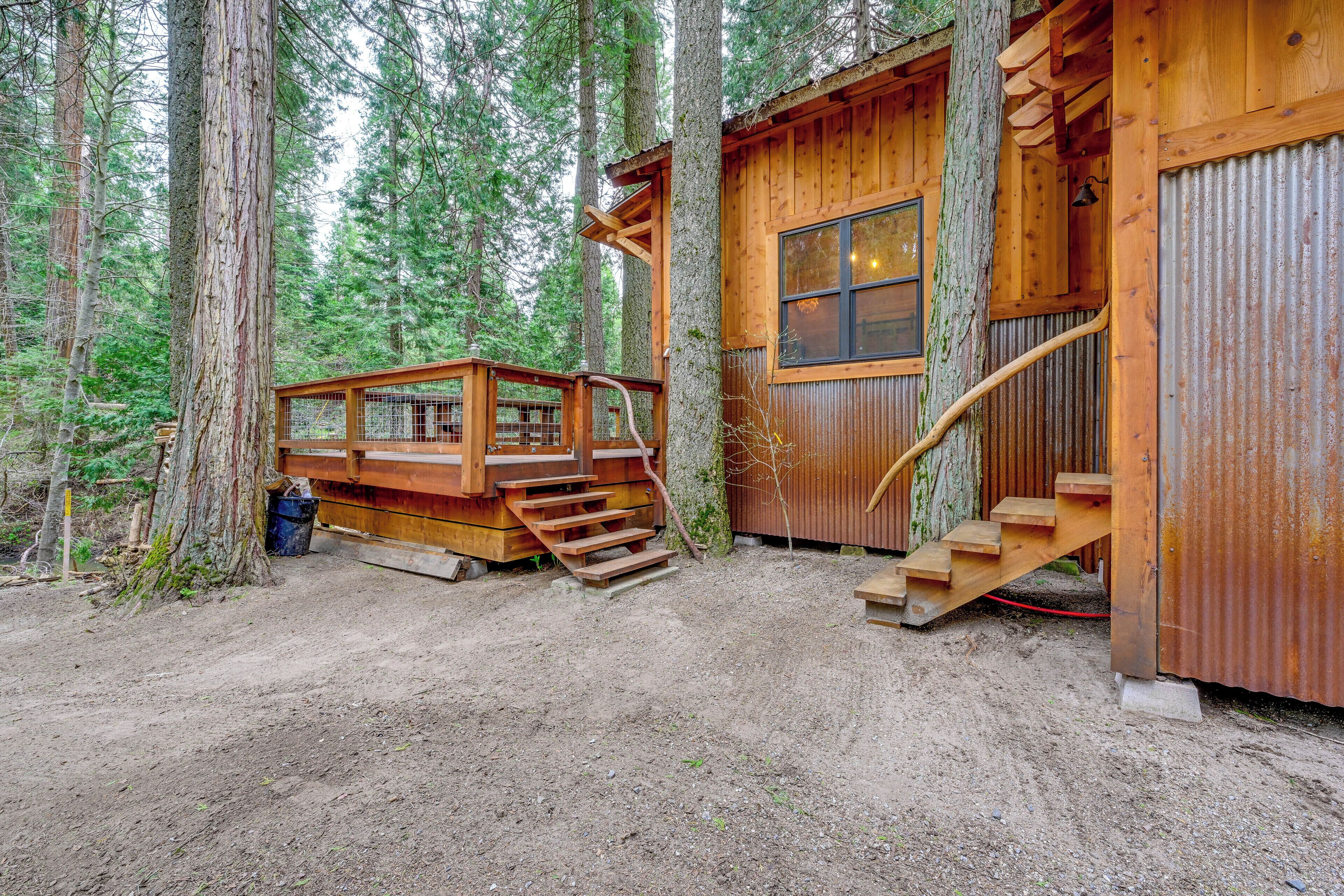 A rustic cabin with a wooden deck and a staircase leading to a wooden door.