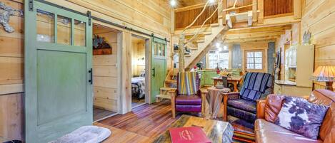 A cozy wooden cabin interior with a sofa, a coffee table, and a striped rug.