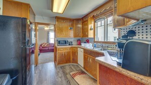 A compact kitchen with wooden cabinets, a microwave, a coffee maker, and a sink. - Cozy Iowa Getaway w/ Patio & Fenced-in Yard! (Dyersville)