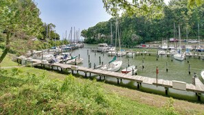 A marina with multiple boats docked at wooden piers, surrounded by greenery and trees. - Walk to Beach: Charming Maryland Home w/ Yard! (St. Leonard)