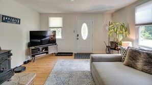A living room with a television, a sofa, a fireplace, and a door with a window. - Walk to Beach: Charming Maryland Home w/ Yard! (St. Leonard)