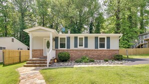 A single-story house with a brick foundation and white siding, a front porch, and a stone pathway leading to the entrance. - Walk to Beach: Charming Maryland Home w/ Yard! (St. Leonard)