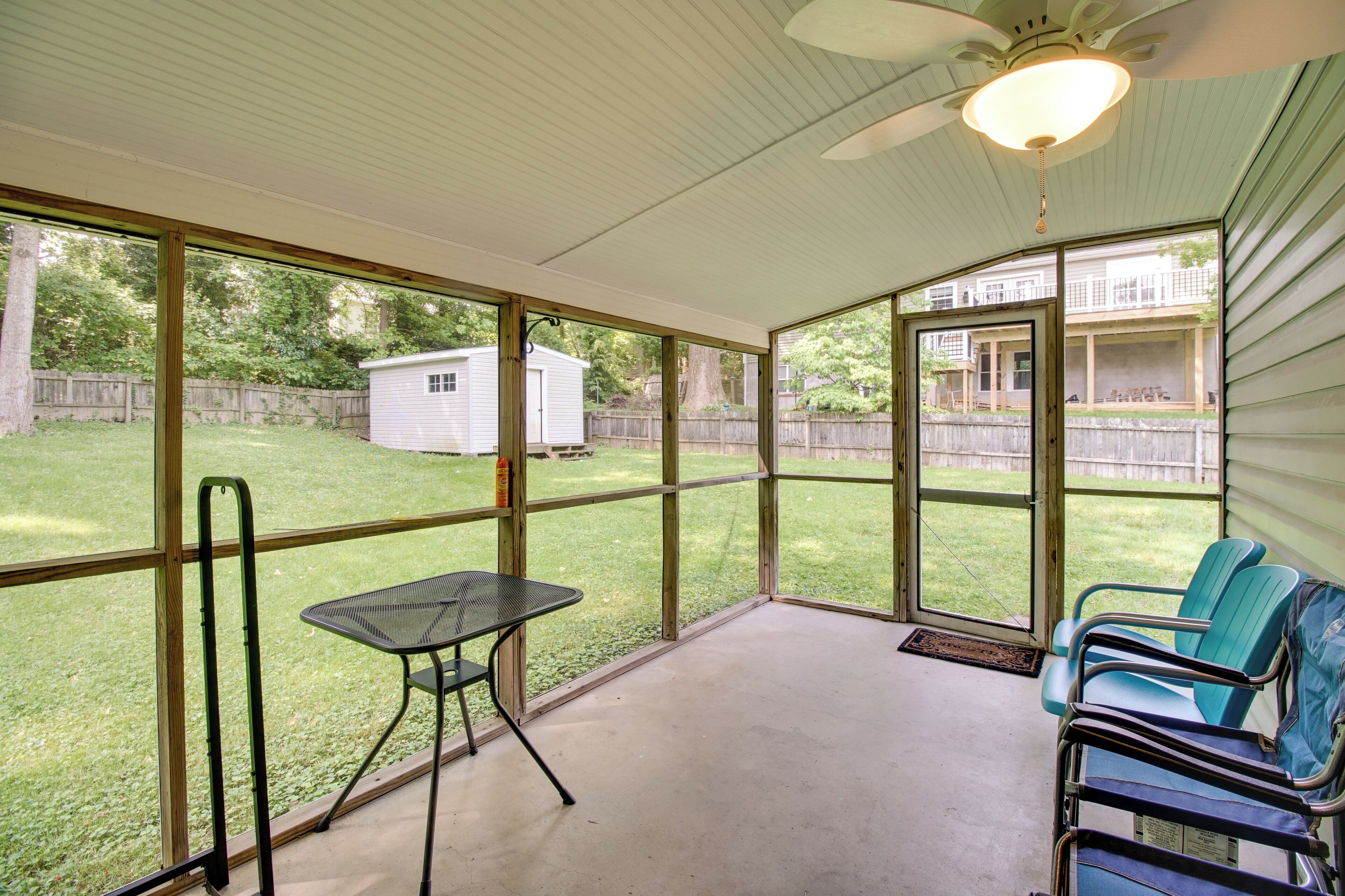 A covered patio with large windows, a metal table, and blue chairs.