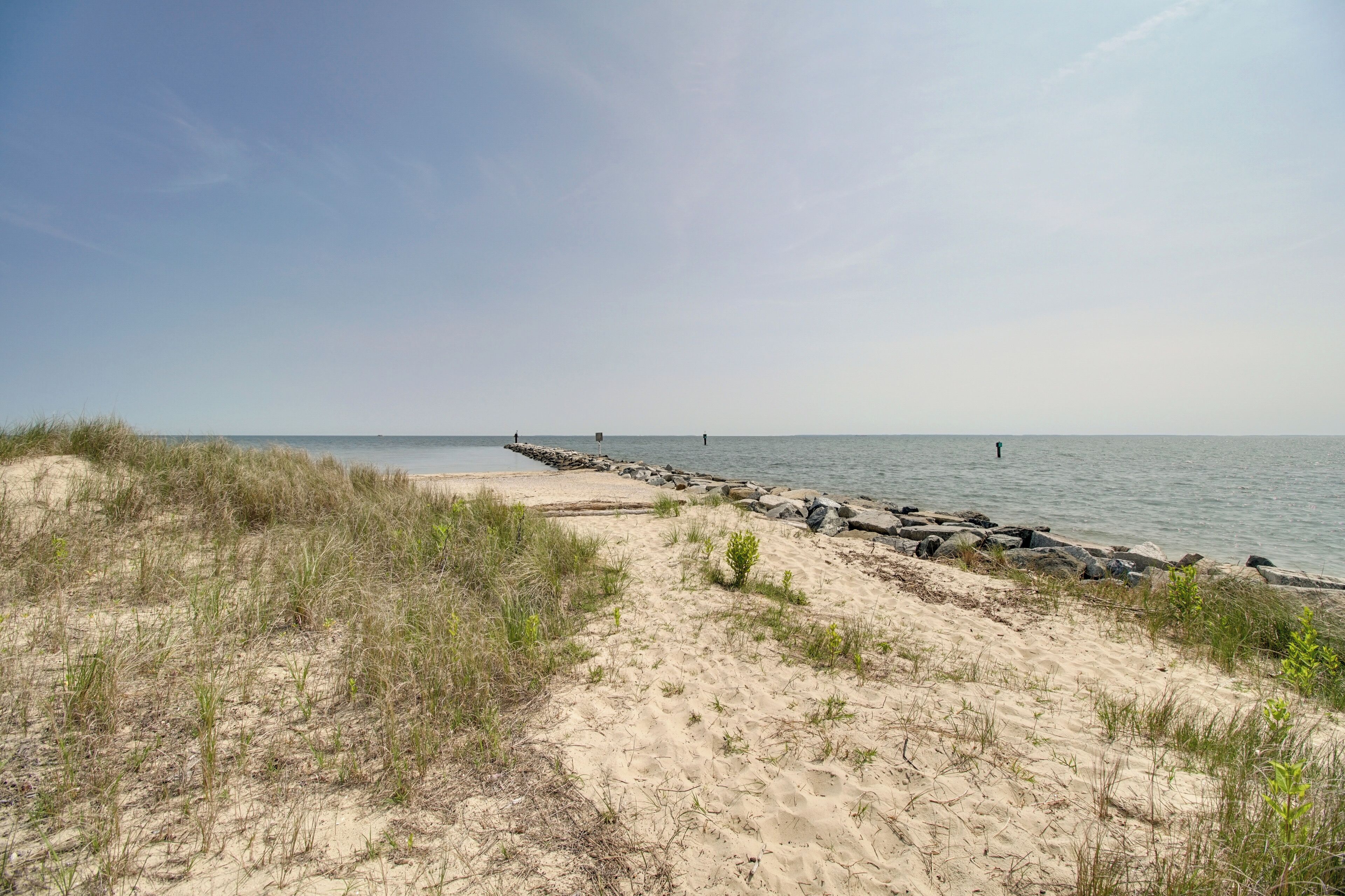 A sandy beach with a rocky breakwater extending into the water.