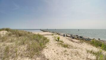 A sandy beach with a rocky breakwater extending into the water.