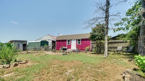 A backyard with a red house, a green shed, and a tree. - Charming Oklahoma Retreat w/ Grill - Pets Welcome! (Spencerville)