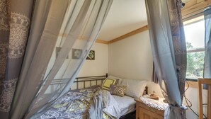 A bedroom with a bed, bedside table, and a window with curtains. - Charming Oklahoma Retreat w/ Grill - Pets Welcome! (Spencerville)