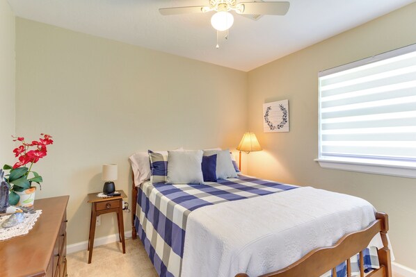 A bedroom with a bed, a nightstand, a lamp, a window with blinds, and a ceiling fan. - Cozy Oklahoma Retreat w/ Covered Patio & Gas Grill (Mustang)