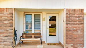A front door with a bench, a doormat, and a hose.