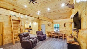 A log cabin interior with a dining area, two leather recliners, a ceiling fan, and mounted animal heads. - Crystal Springs Cabin, 4 Mi to Calling Panther! (Crystal Springs)