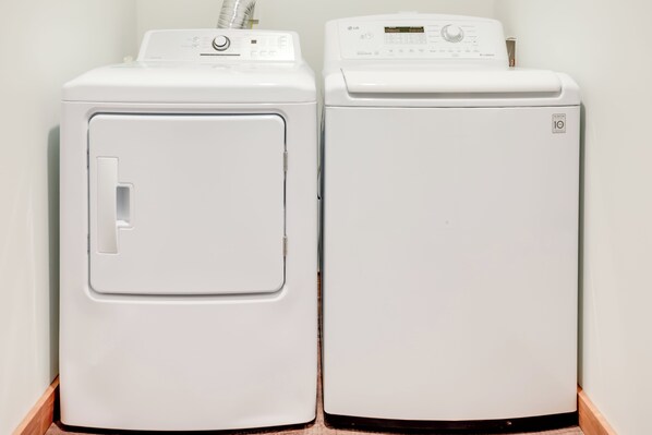 Dos lavadoras blancas de carga frontal una al lado de la otra en un cuarto de lavado.