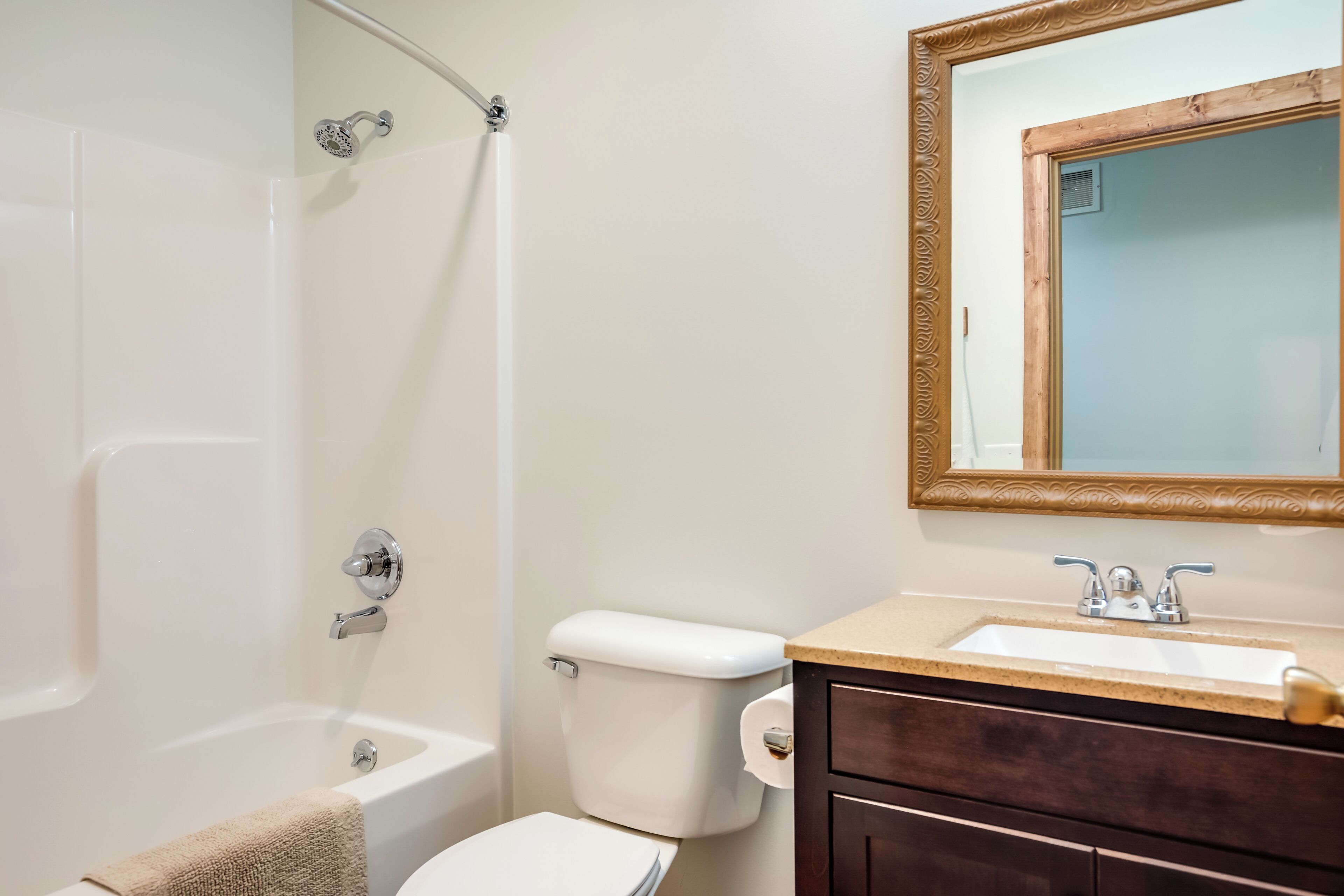A bathroom with a bathtub, toilet, sink, and a mirror with an ornate frame.