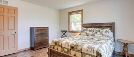 A bedroom with a wooden bed, a dresser, a window, and a small table.