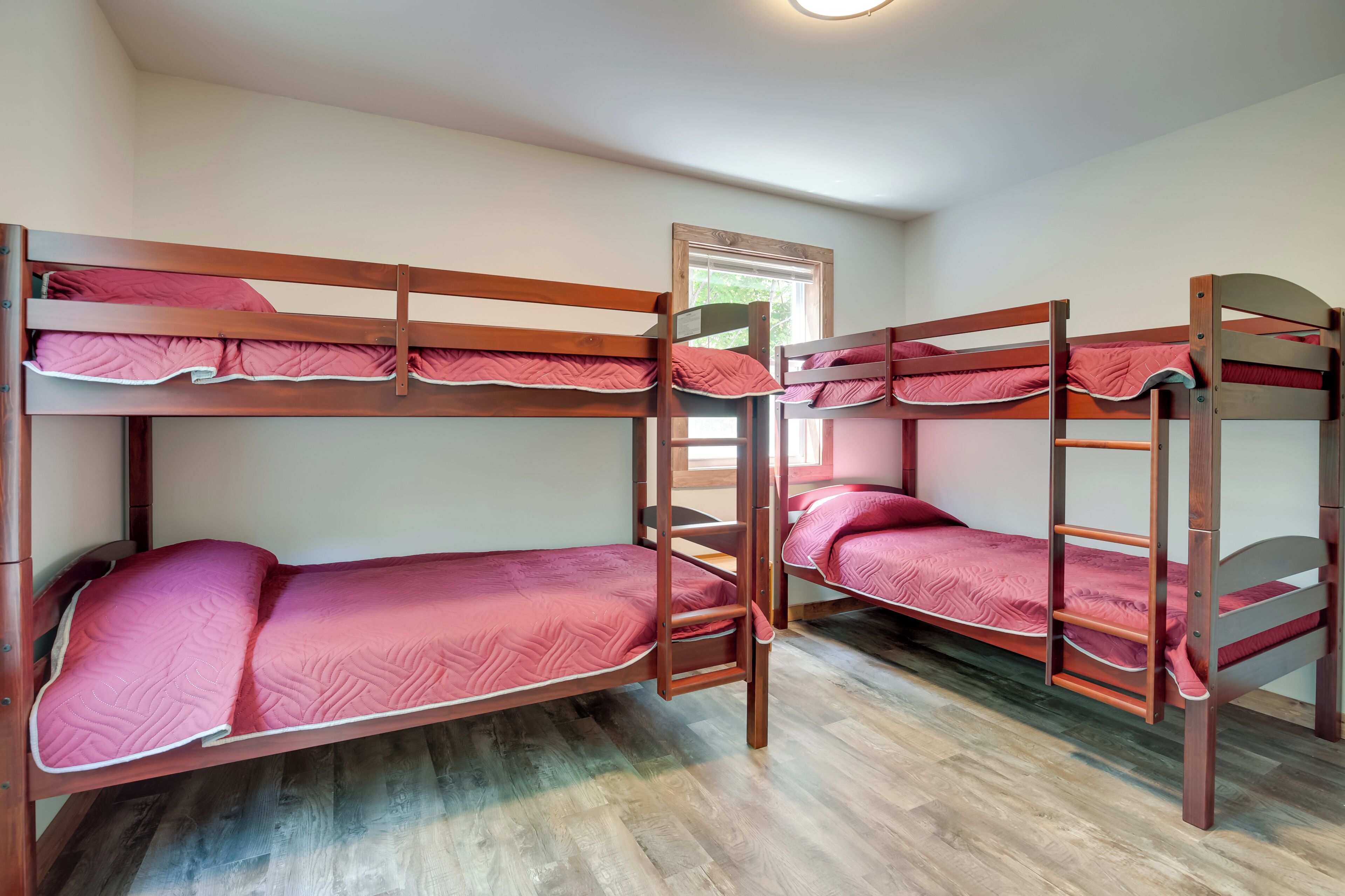 A bunk bed room with wooden frames and red bedding.