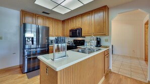 A modern kitchen with wooden cabinets, stainless steel appliances, and a large island.