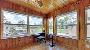 A room with wooden paneled walls and large windows offering a view of a residential area.