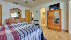 A bedroom with a bed, wooden dresser, and a ceiling fan.