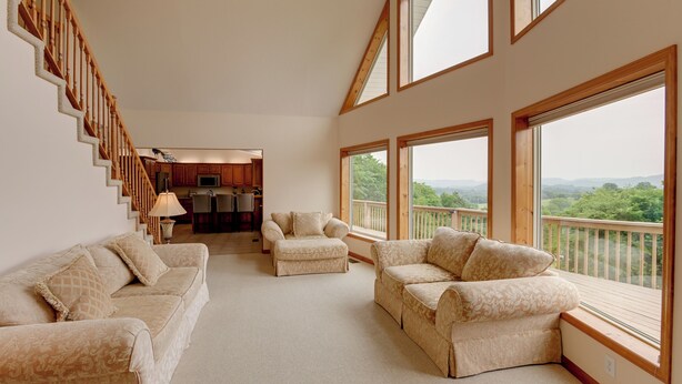 A spacious living area with a high ceiling, large windows offering a view of the outdoors, and a kitchen in the background. - Gordonsville Retreat: Deck w/ Spectacular Views! (Gordonsville)