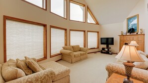 A spacious living room with a high ceiling, large windows, a television, and a fireplace. - Gordonsville Retreat: Deck w/ Spectacular Views! (Gordonsville)