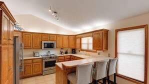 A kitchen with wooden cabinets, a refrigerator, a microwave, an oven, and a coffee maker. There is a bar area with stools. - Gordonsville Retreat: Deck w/ Spectacular Views! (Gordonsville)