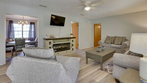 A living room with a fireplace, a television, and a ceiling fan. - Pet-friendly Slocomb Vacation Rental w/ Sunroom! (Slocomb)