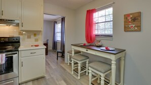 A kitchen with white cabinets, a stove, and a dining area with a table and two chairs. - Pet-friendly Slocomb Vacation Rental w/ Sunroom! (Slocomb)
