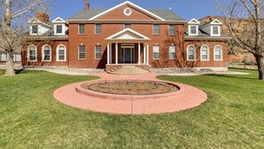 A large brick building with a central entrance, symmetrical windows, and a circular driveway. - Spacious Hildale House w/ Large Deck! (Hildale)