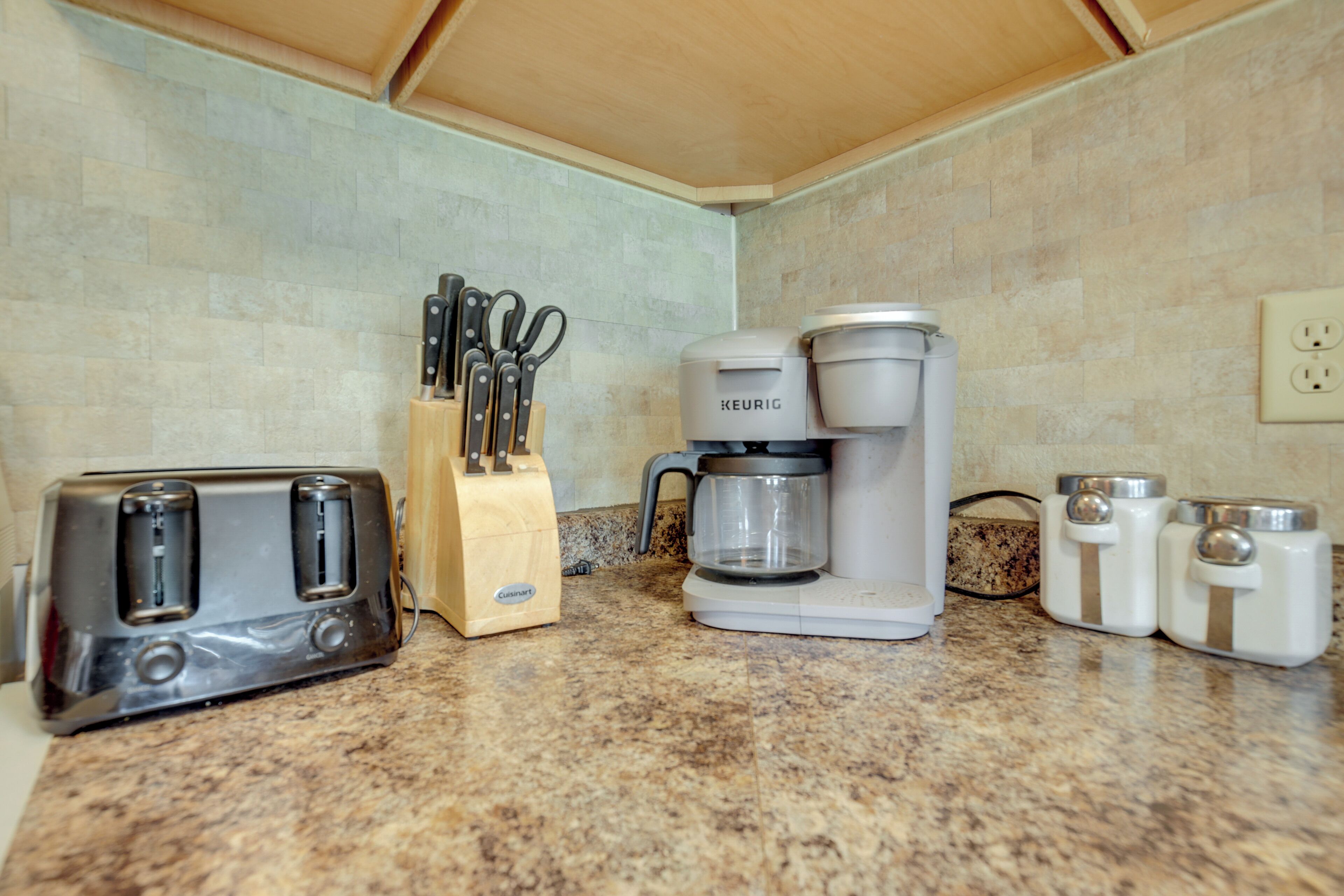 Une cuisine équipée d’un grille-pain, d’une machine à café, d’un bloc à couteaux et de salières et de poivrières sur le plan de travail.