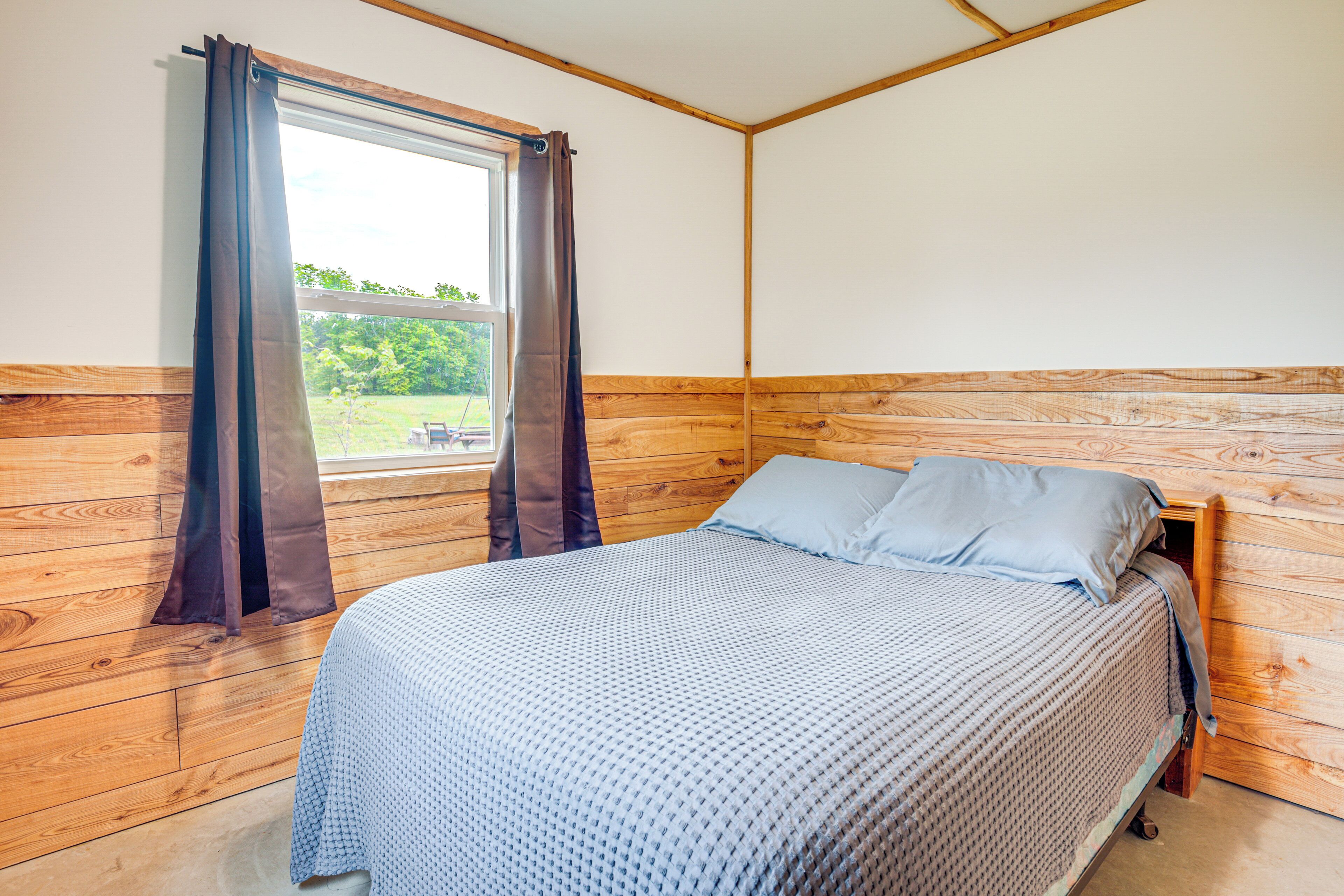 Un dormitorio con cabecera de madera, una cama con colcha estampada y una ventana con cortinas.