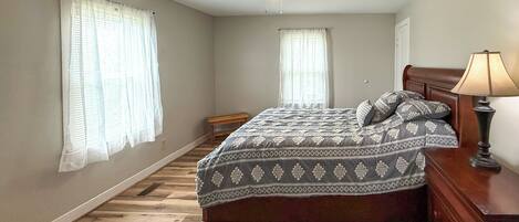 A bedroom with a bed, a ceiling fan, a nightstand, and a lamp.