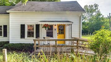 Traditional home with a charming front porch and lush green surroundings.