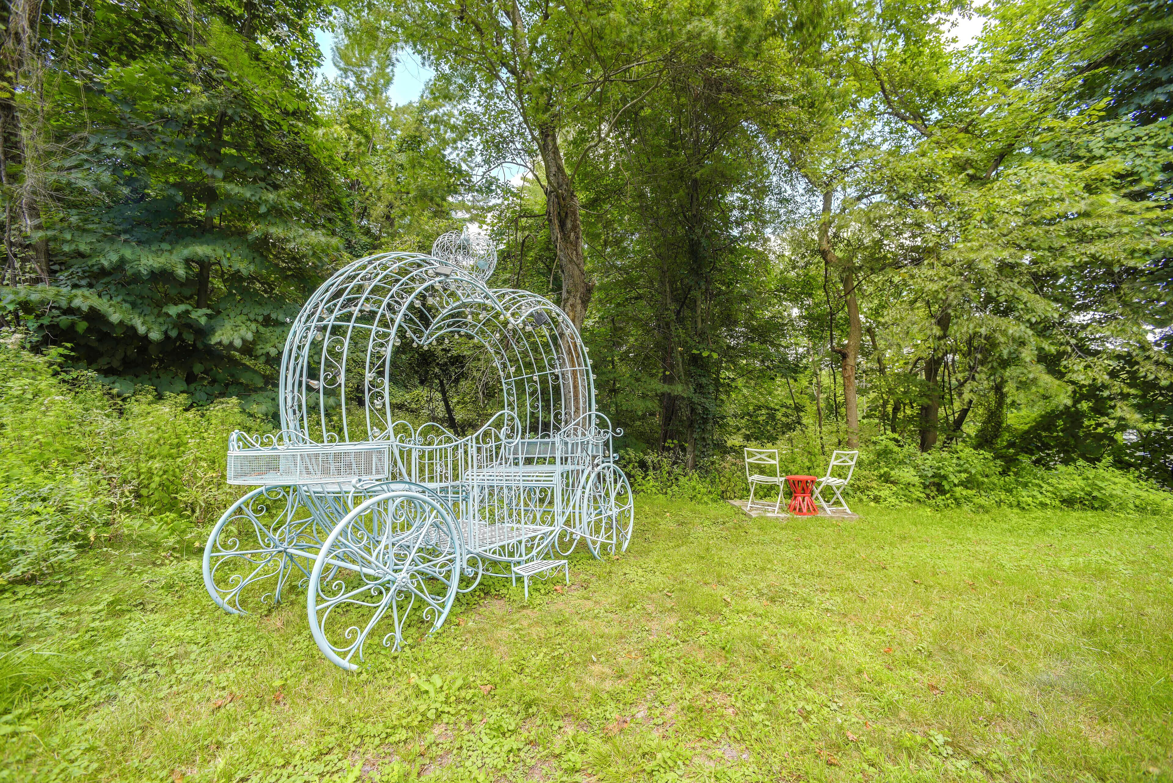 A metal carriage structure in a park with benches and a red table.