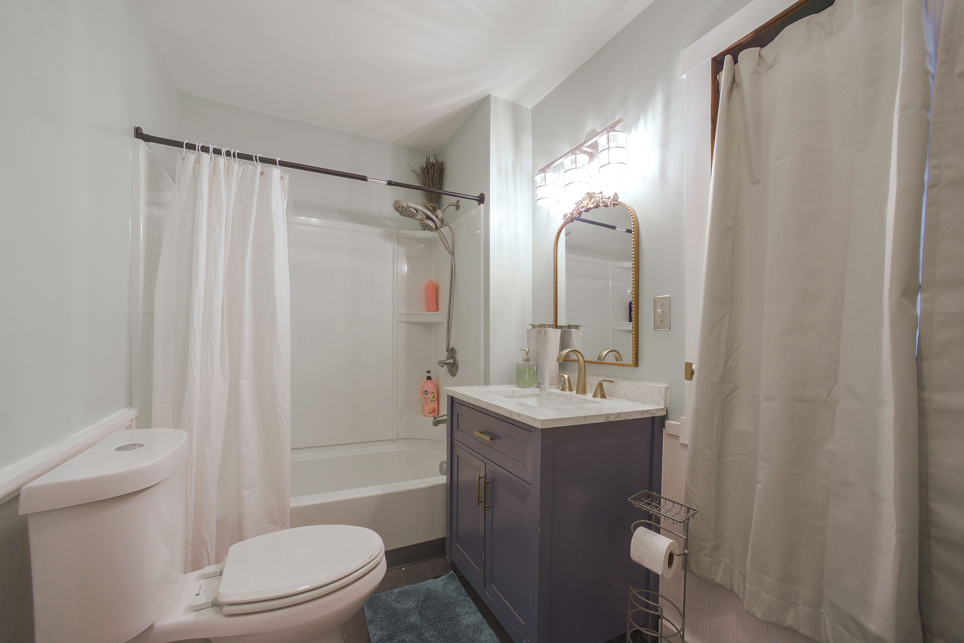 Een badkamer met toilet, badkuip, douche, wastafel met spiegel en een handdoekrek.