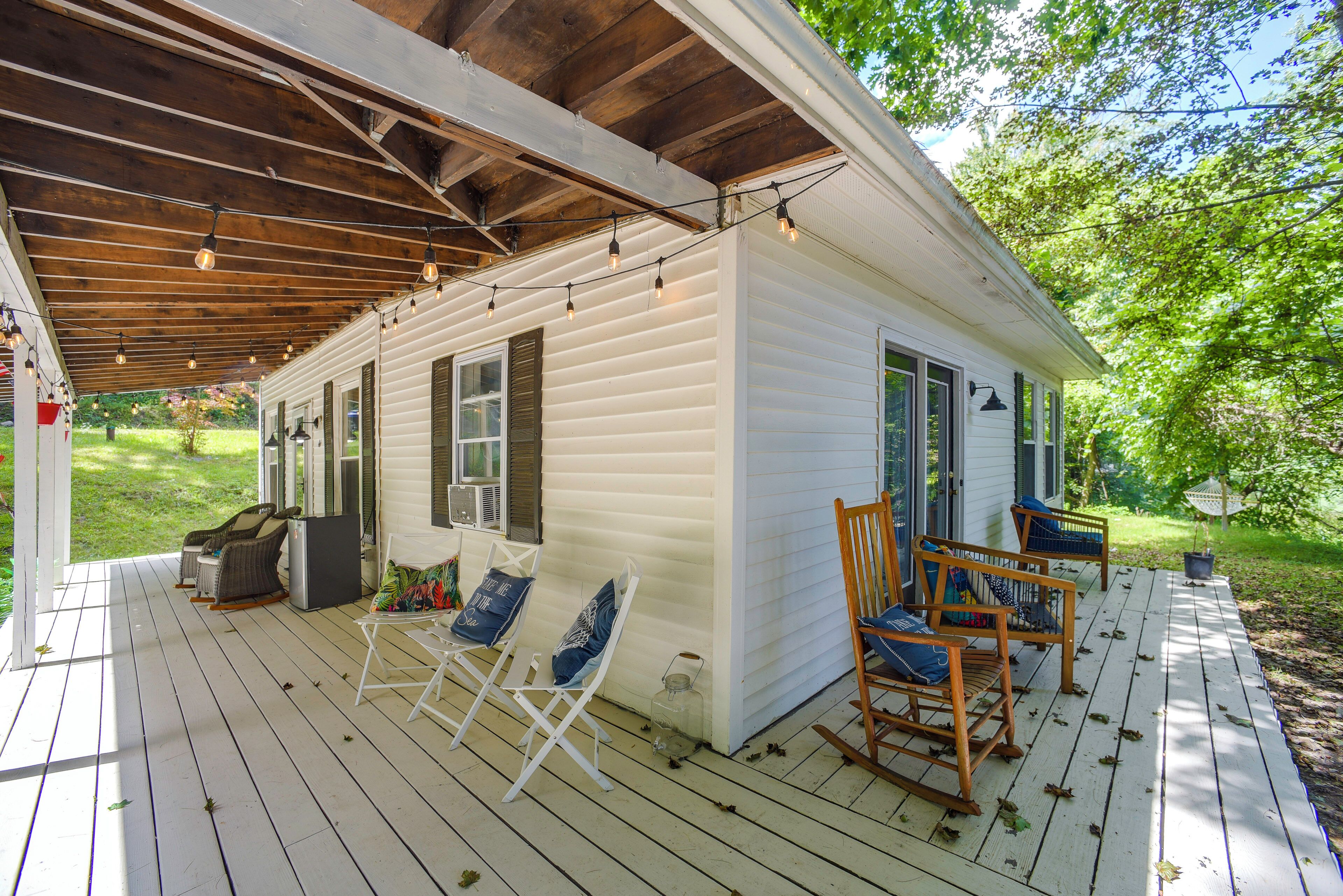 A covered porch with outdoor seating and a small house.