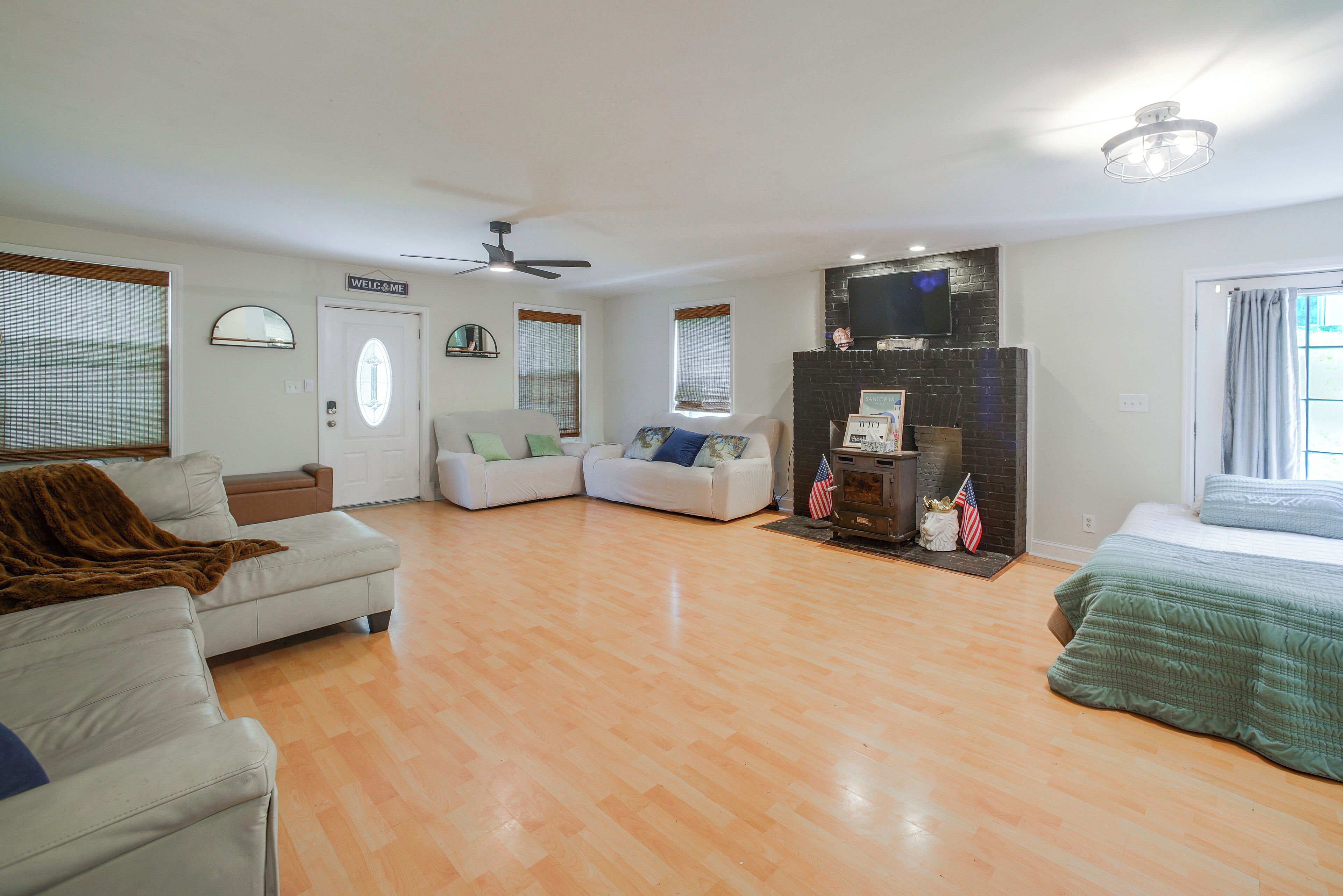 A spacious living area with a fireplace, a ceiling fan, and a television mounted on the wall.