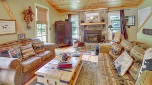 A cozy living room with a fireplace, leather sofas, and a stone fireplace surround.