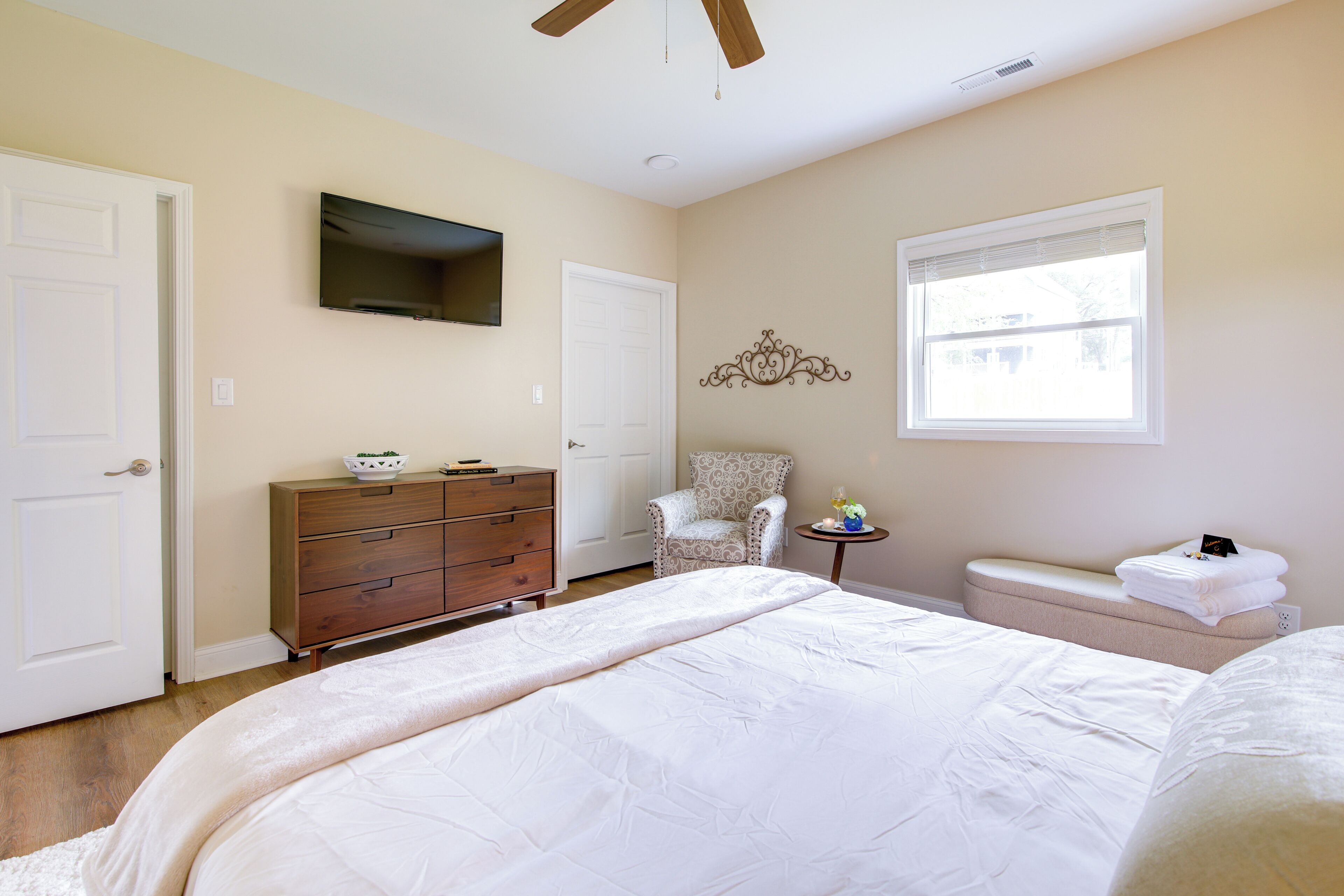 Quarto com cama, penteadeira, cadeira e uma mesinha de cabeceira com abajur.