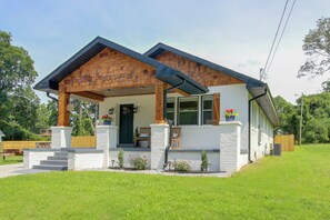 A modern house with a covered porch, white exterior walls, and a brick roof.