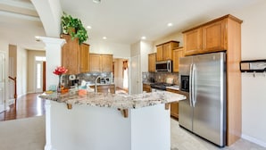 A spacious kitchen with wooden cabinets, a stainless steel refrigerator, and a granite countertop island. - Charming Pennsylvania Retreat w/ Deck & Fireplace! (Willow Street)