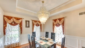 A dining room with a glass table, six chairs, a chandelier, and ornate curtains. - Charming Pennsylvania Retreat w/ Deck & Fireplace! (Willow Street)