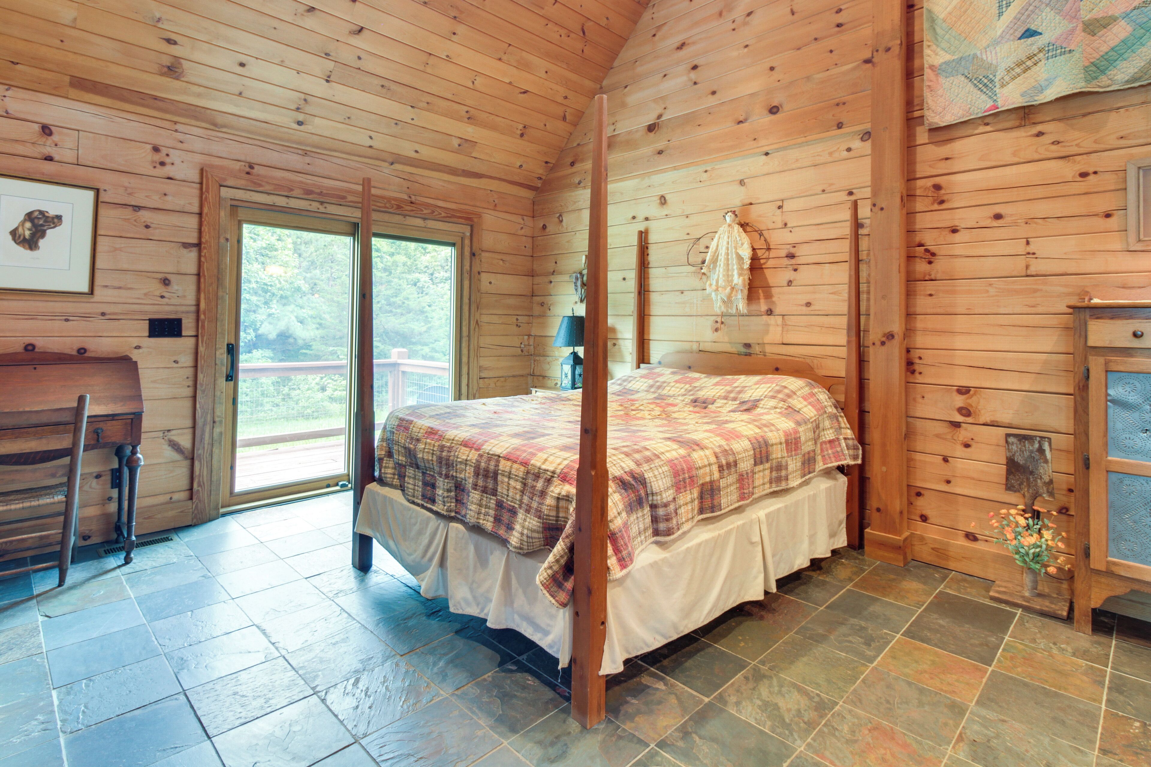 Ein Schlafzimmer einer Holzhütte mit einem Himmelbett, einem Holztisch und einem großen Fenster.