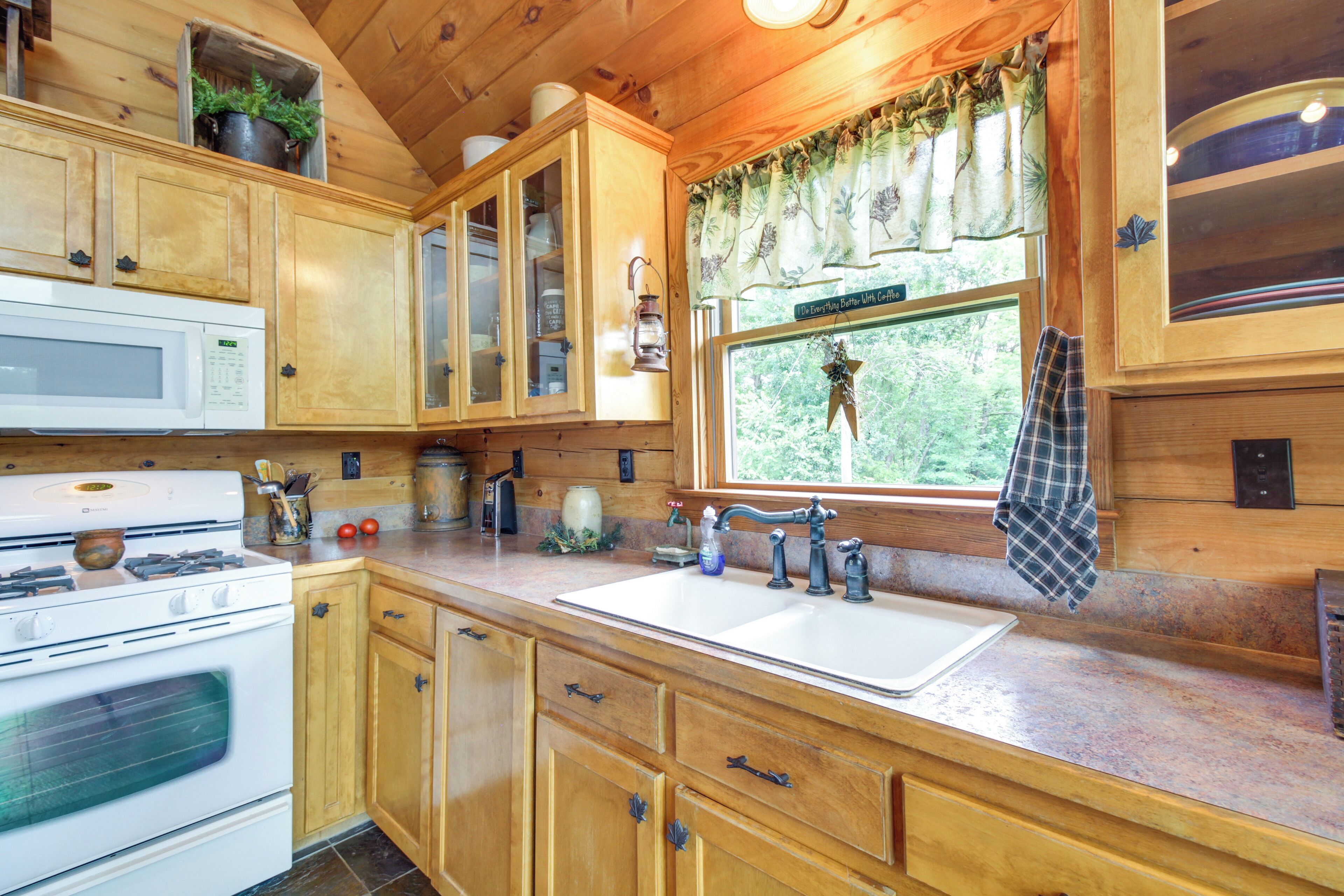 A wooden kitchen with a white stove, a sink, and cabinets.