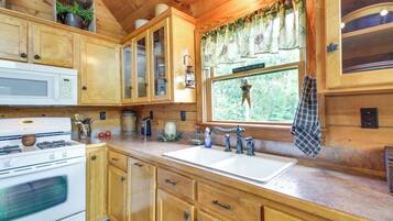 A wooden kitchen with a white stove, a sink, and cabinets.