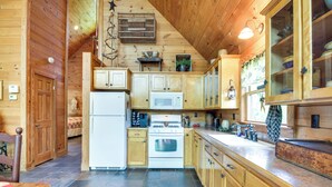 A wooden cabin interior with a kitchen featuring a refrigerator, stove, microwave, and wooden cabinets. - 12 Mi to Staunton River: Nathalie Cabin w/ Deck (Nathalie)