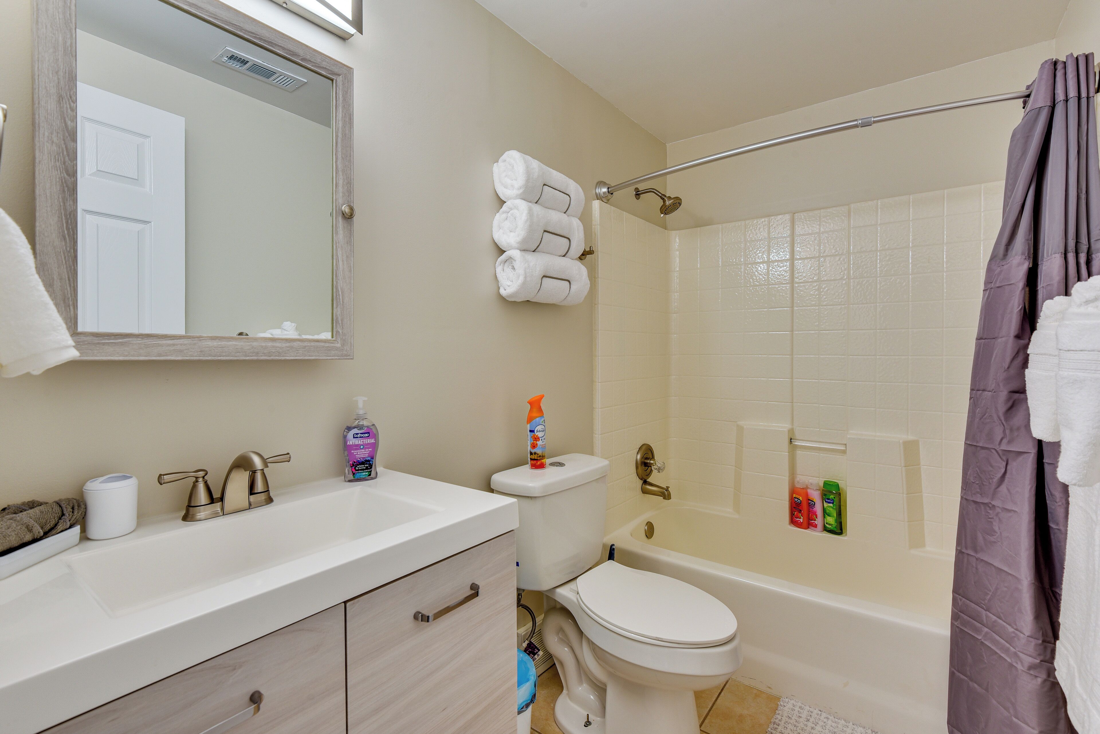 A bathroom with a sink, toilet, and bathtub. There are towels hanging on the wall and a shower curtain.