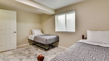 A bedroom with two beds, a door, a window, and a ceiling vent.