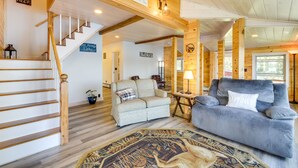Interior acogedor de una cabaña con una escalera de madera, un sofá, una alfombra y un letrero que dice 'Lake House'.