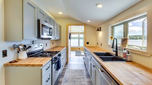 Una cocina moderna con encimeras de madera, electrodomésticos de acero inoxidable y vistas a través de la puerta.